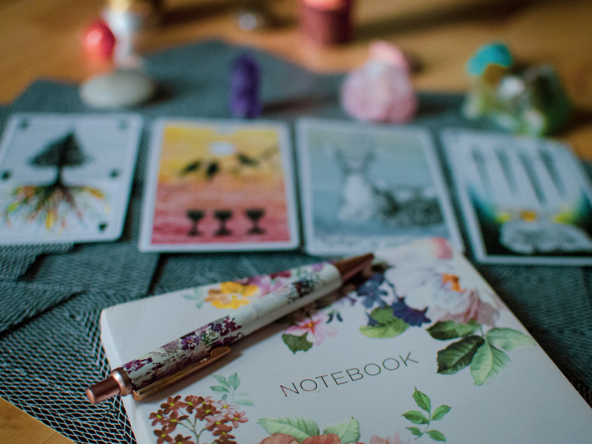 A journal with a pen on it, sitting in front of tarot cards